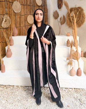 Woman in a black and white outfit standing in a decorative setting with straw walls and decor.