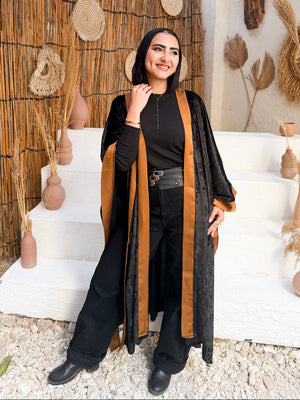 Woman standing in a rustic interior setting with decorative elements and a thatched roof.