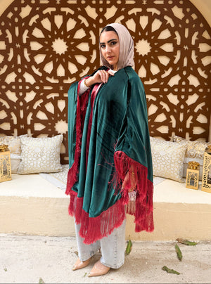 Woman wearing a teal and red shawl in a decorated room with an intricate wall design.