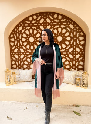 Woman in a green cardigan and black outfit standing in front of an ornate wall design.