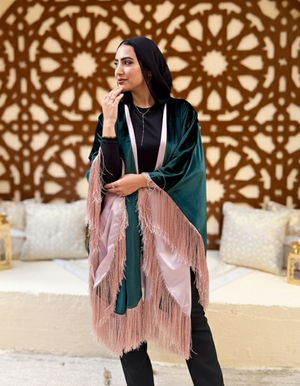 Woman in a green and pink outfit standing in front of an ornate wall design.