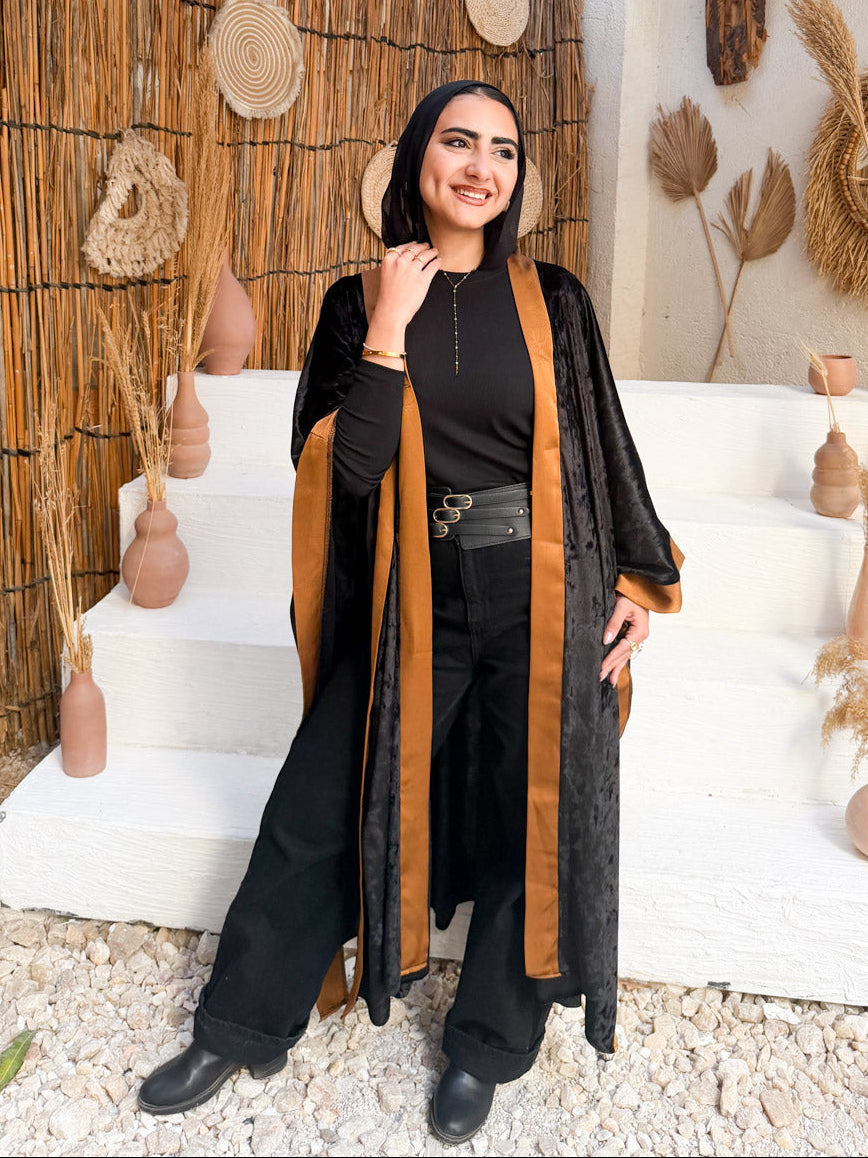 Woman standing in a rustic interior setting with decorative elements and a thatched roof.