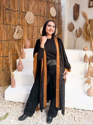 Woman standing in a rustic interior setting with decorative elements and a thatched roof.