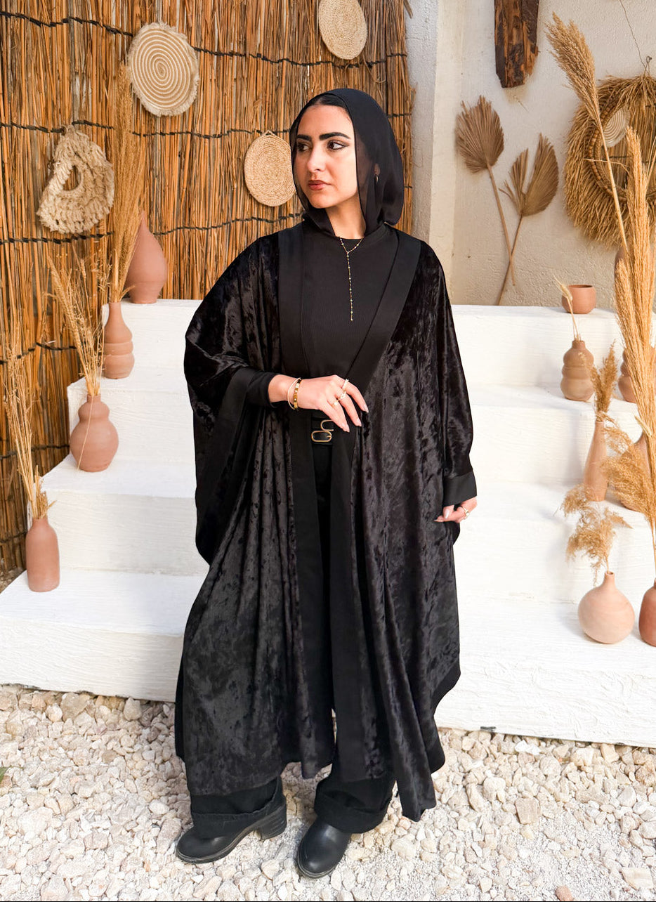Woman in a black outfit standing in a decorative indoor setting with wicker walls and decor.