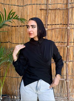 Woman wearing a black hijab and black shirt against a reed wall